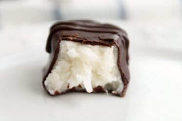 Chocolate dipped coconut cream egg with a bite taken out of it.