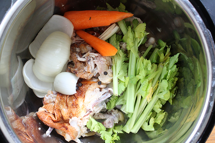 Instant Pot full of Chicken bones, celery, onions and carrots. 