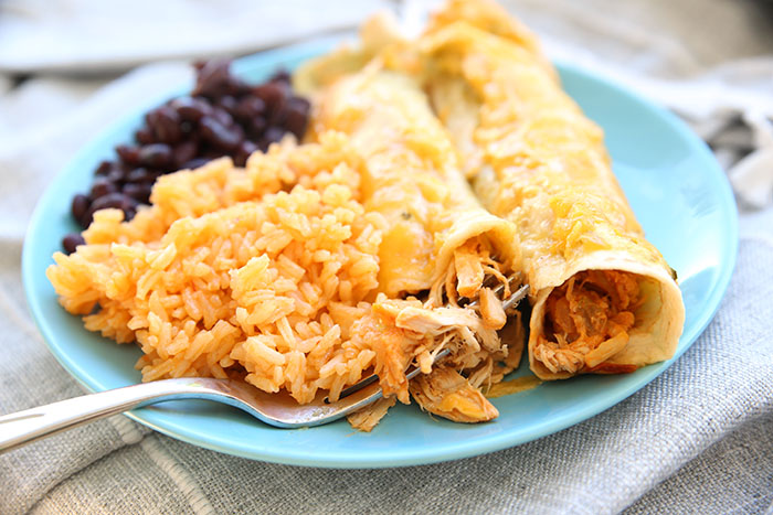 Blue plate with spanish rice, black beans and two chicken enchiladas