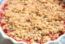 Beautiful strawberry rhubarb crisp in a polish pottery pie dish. you can see the red fruit juices around the edges and the rest of the picture highlights the delicious crisp topping.