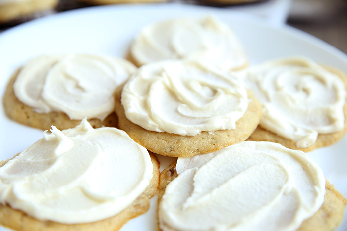 white plate full of fluffy banana cookies with white buttercream frosting