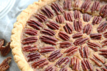 dear abby famous pecan pie on a table cloth with the utensils needed to serve it nearby.