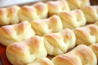 sheet pan of parker house rolls, folded over like a pocket roll, they are nicely browned on top and in rows