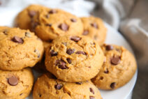 a plate of pumpkin chocolate chip cookies, the plate is sitting on a grey table cloth