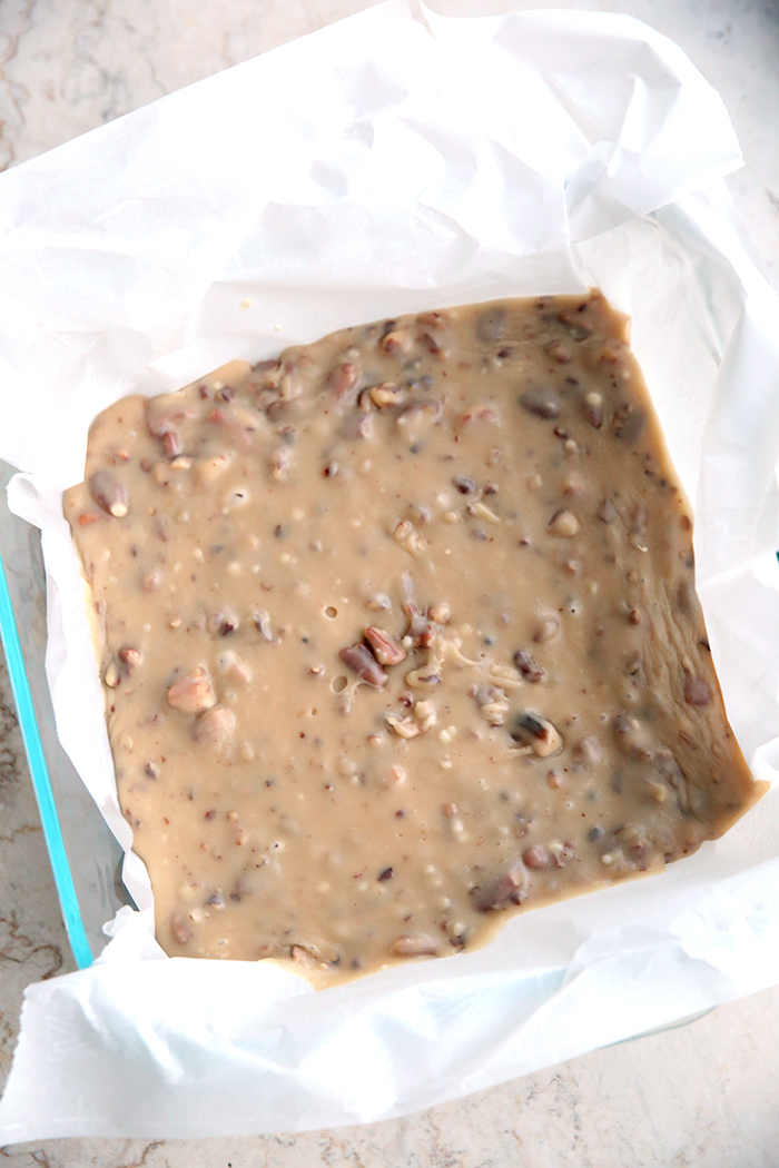 a 8x8 pan of butter pecan fudge that has not been cut yet. It is beige in color and you can see pieces of pecan in it.