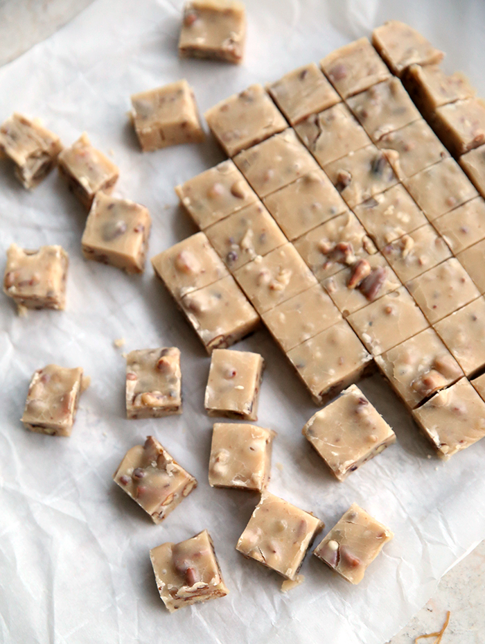 a bunch of cut up fudge on parchment paper. the fudge is cut into one inch squares.