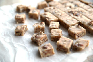 butter pecan fudge cut into one inch squares sitting on a piece of parchment paper