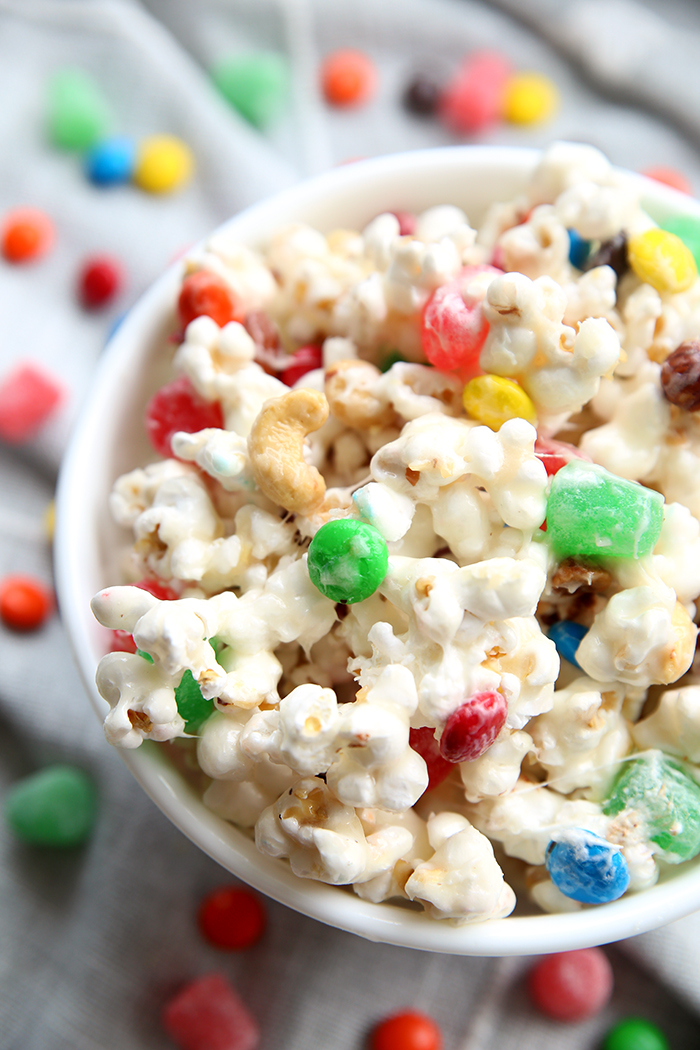 a small bowl of popcorn with candy inside and around it. the candy is colorful