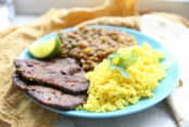 Authentic carne asada with a side of ecuadorian lentil soup and ecuadorian yellow rice on a blue plate.