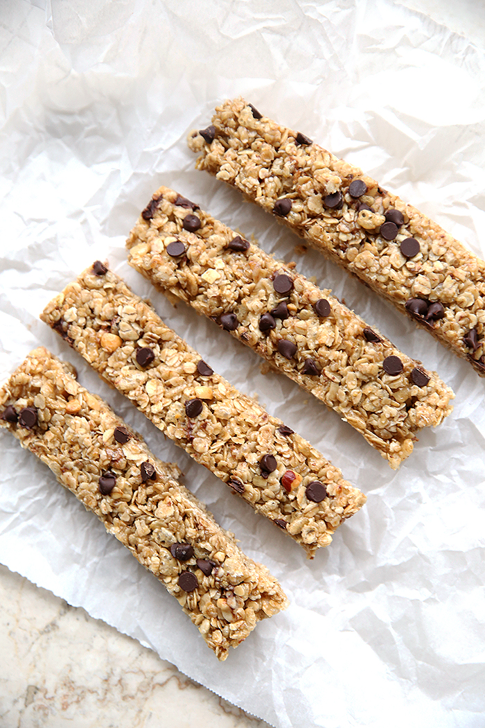 Four Chewy Peanut Butter Chocolate Chip Granola Bars sitting on parchment paper.