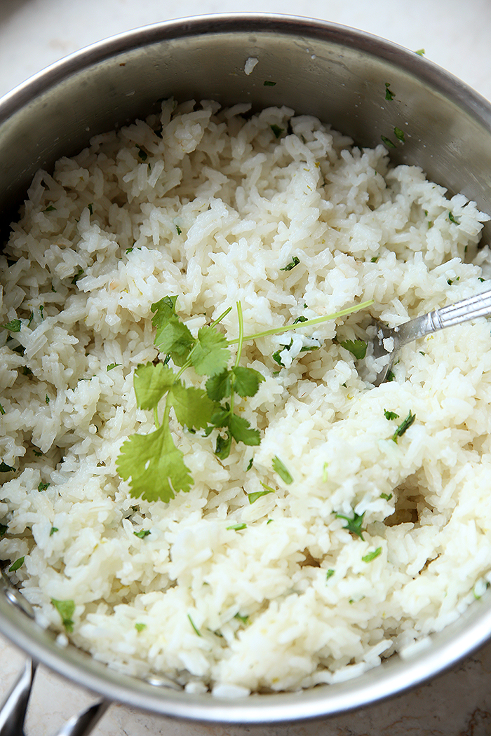 A large pot of Copycat Chipotle Cilantro Lime Rice. A silver spoon is halfway in the top of the rice.