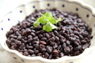A white scalloped bowl holding Instant Pot black beans with cilantro on top