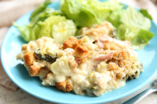 Romain lettuce and chicken casserole sitting on a light-blue plate with a picture of a fork handle in the right-hand corner. At the top in the background, there's a partial picture of a beige cloth napkin.