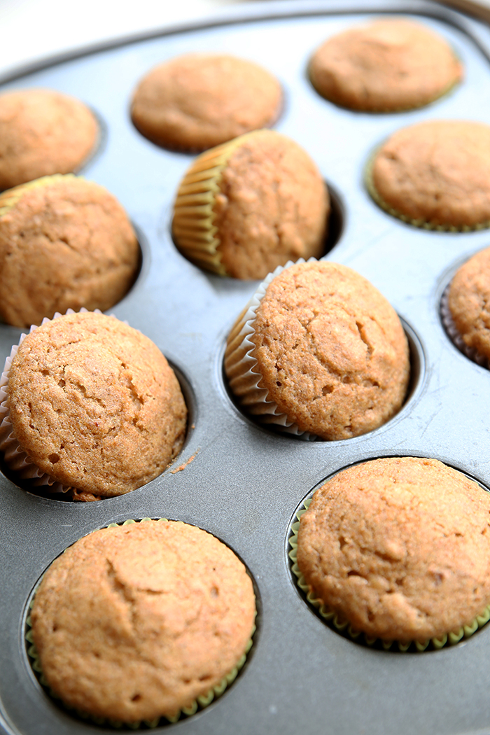 A muffin pan full of Refrigerator Bran Muffins with four of the muffins titled on the side.