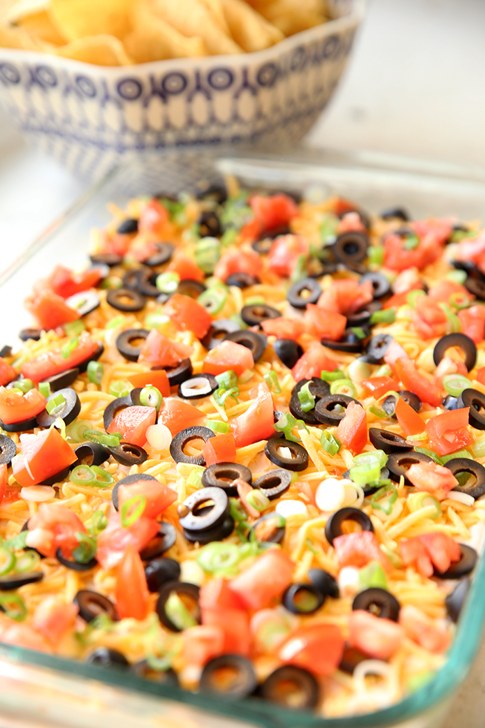 A glass dish holding ultimate seven layer dip