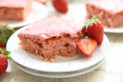 Slice of strawberry jam cake on a white plate with strawberries