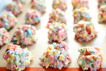 Rows of Fruity Pebble Treats on a lined cookie sheet