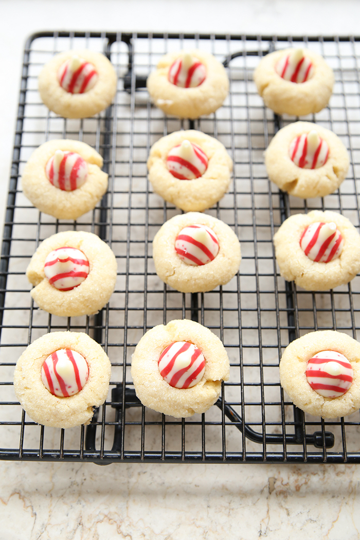 12 Shortbread Peppermint Kiss Cookies sitting on a wire cooling rack.