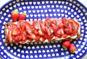 Strawberry Nutella Puff Pastry Dessert with two whole strawberries on opposite diagonal ends, all sitting on an oval dark blue Polish Pottery plate with a white hearts pattern