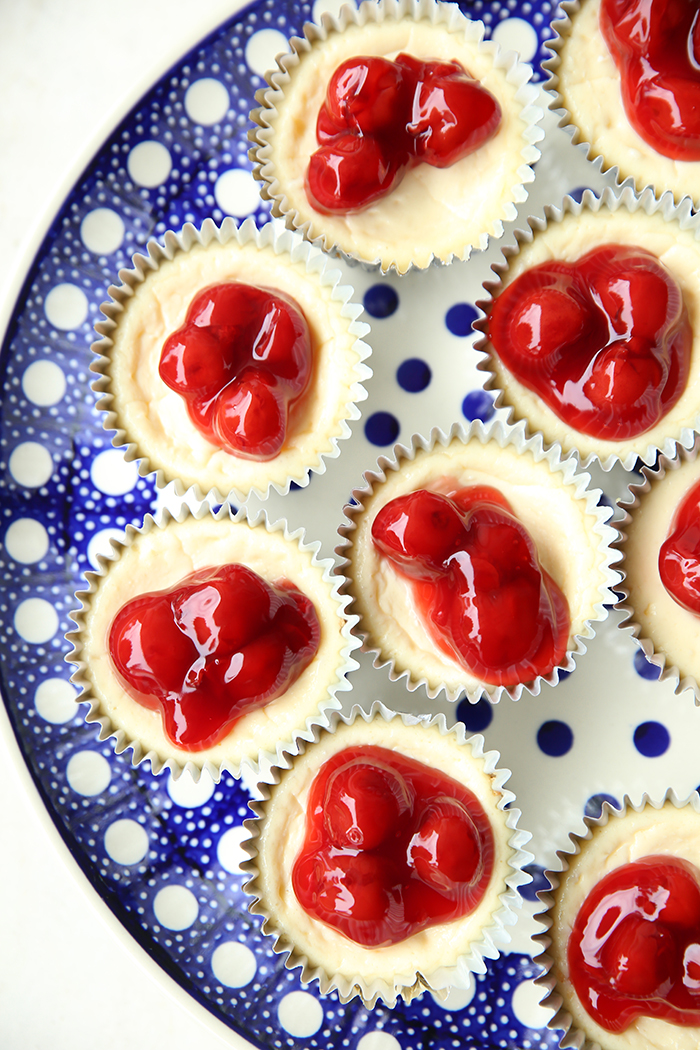 Mini Cherry Cheesecakes on a large white and blue polka dotted plate.