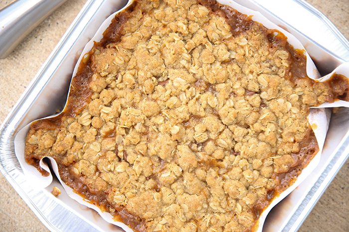 An 8x8 baking dish lined with parchment paper full of Carmelita bars.