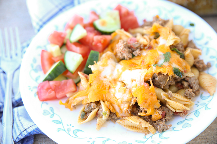 plate of cheesy taco pasta casserole with a side salad on it.