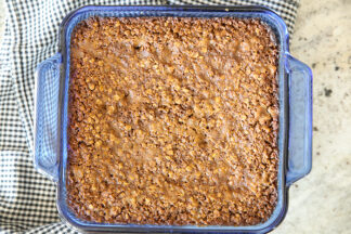 Gingerbread baked oatmeal in a glass 8x8 dish on top of a small checked dish towel.