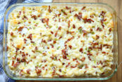 A glass 9x13 baking dish of Loaded Pepper Jack Mac and Cheese sitting partially on a white and blue flannel patterned kitchen towel.