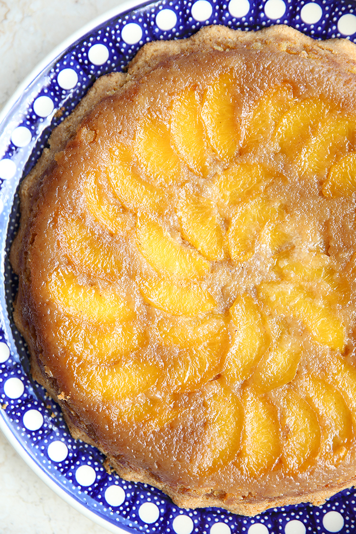 Upside Down Peach Cake in a round Polish pottery dish with polka dots.