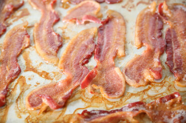 A cookie sheet full of oven-baked thick slices of bacon.