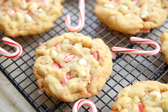 A cooling rack with small candy canes and peppermint cookies with white chocolate chips.