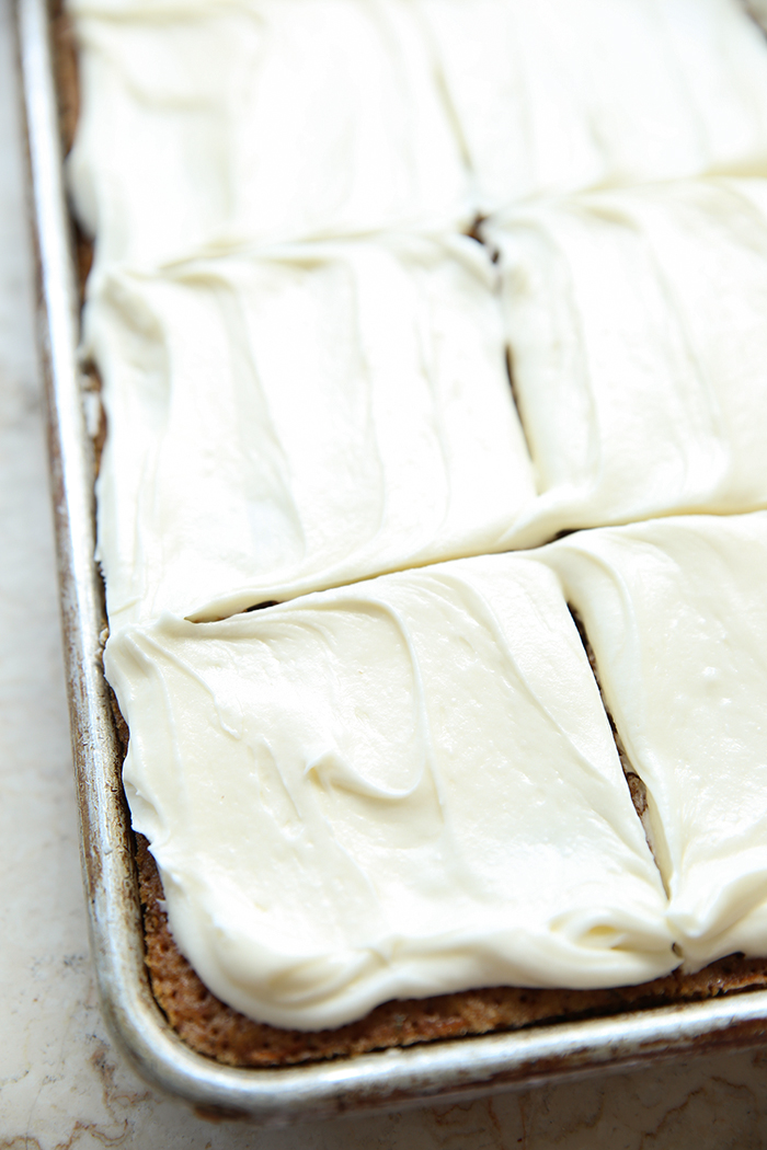 Zucchini sheet cake frosted with cream cheese frosting cut into squares.
