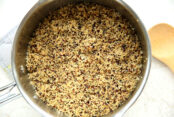 A pot of multicolored quinoa with a wooden cooking spoon on the right.