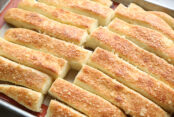 Baked garlic parmesan breadsticks on a large baking sheet with a silicone mat.