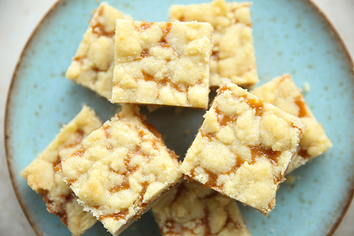 A plate salted caramel crush squares with the squares stacked on top of each other.