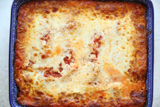 Roasted red pepper lasagna in a dark blue rectangle Polish pottery baking dish.