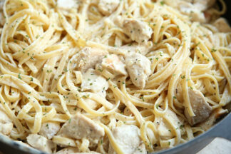 A partial picture of lemon chicken pasta in a black skillet.