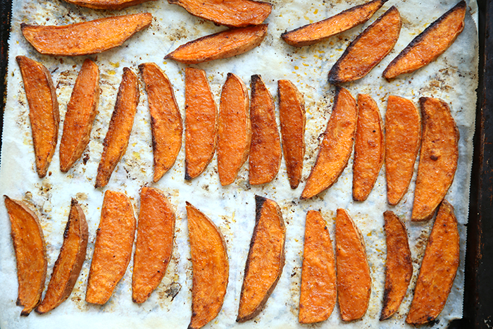 Baked Sweet Potato Wedges on a baking sheet covered in parchment paper.