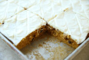 Cut Pumpkin Chocolate Chip Bars with Cream Cheese Frosting in a large cookie sheet with a piece missing from a corner.