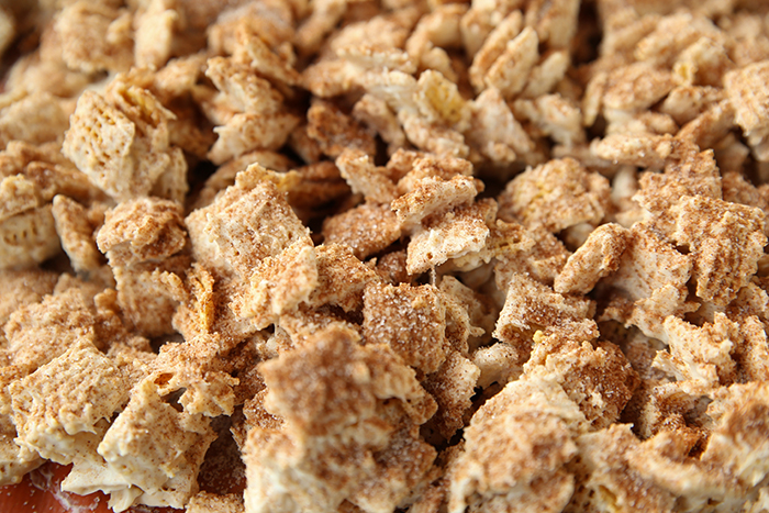 A baking sheet full of churro muddy buddies sprinkled with cinnamon sugar.