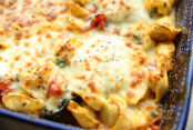 The corner of a dark blue Polish pottery 9x13 dish filled with Easy Baked Tortellini Casserole.
