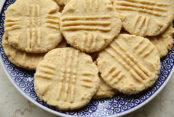 A plate with small swirling dark blue pattern filled with Classic Peanut Butter Cookies.