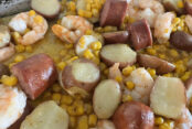 Sweet corn, small red potatoes cut in half, Kielbasa pieces, and shrimp on a sheet pan.