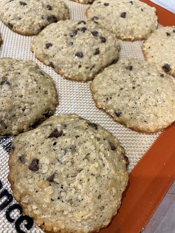 A closeup photo of banana oatmeal cookies on a baking sheet lined with a silicone baking mat.