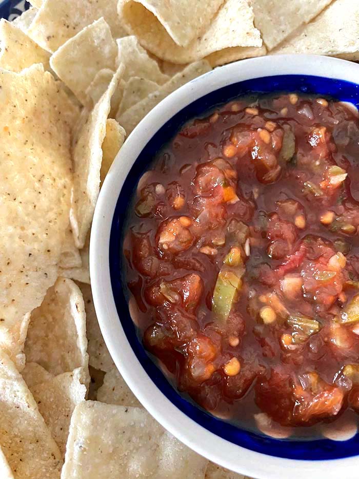A bowl of homemade salsa surrounded by tortilla chips.
