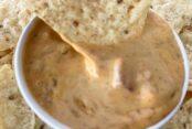 Velveeta Fiesta Dip in a small bowl surrounding by corn chips.