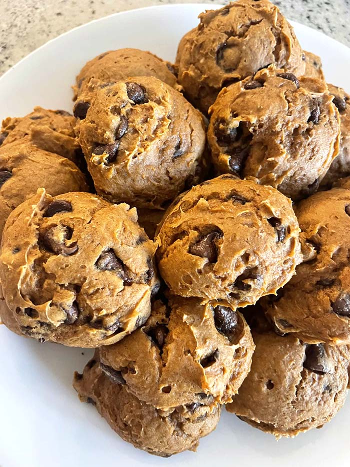 A plate full of chocolate chip pumpkin cookies stacked on each other.