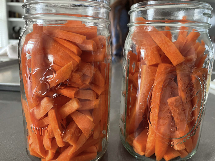 Two half-quart canning glass jars filled with carrot sticks.