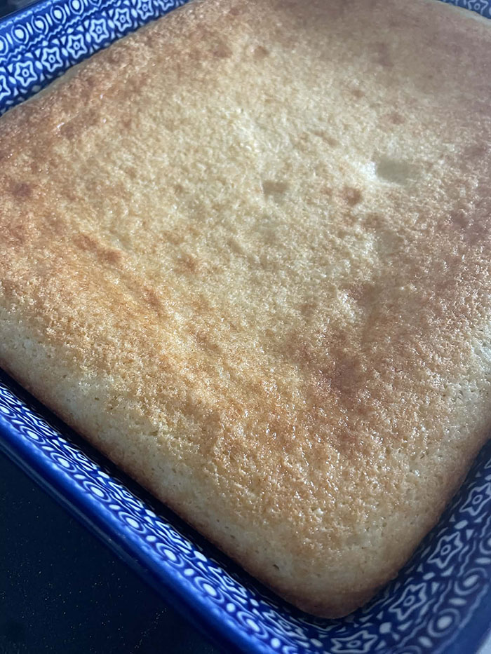 An unfrosted Coconut Cake in a dark blue and white patterned 9x13 Polish Pottery baking dish.