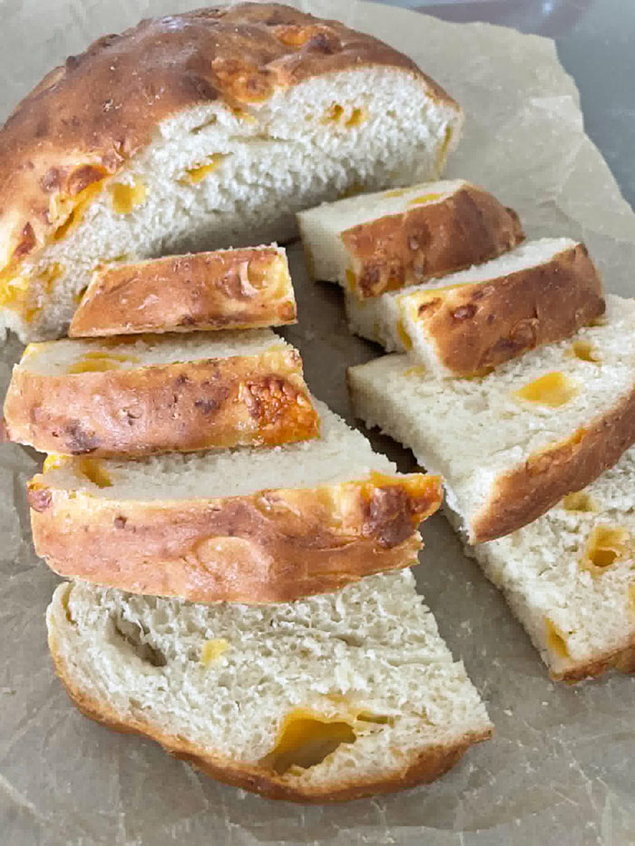 Easy Cheesy Bread sliced in half with one half sliced into 8 pieces sitting on parchment paper.